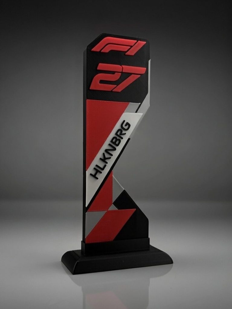 Nico Hülkenberg Audi Revolut F1 Team Ein stilisierter F1-Trophäe mit rot-schwarz-weißen Designelementen.